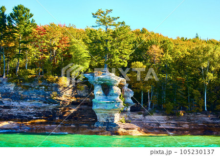 Sea green waters lapping at cliff wall at Pictured Rocks with painted stone cliffs and summer forest Sea green waters lapping at cliff wall at Pictured Rocks with painted stone cliffs and summer forest 105230137