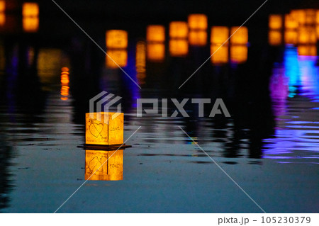 Lone lantern on dark pond with neon lights and distant lanterns in background Lone lantern on dark pond with neon lights and distant lanterns in background 105230379