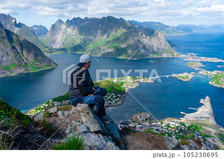 Relaxed happy hiker enjoys stunning views on Reinebringen peaks of Lofoten islands, fjords, Norway Relaxed happy hiker enjoys stunning views on Reinebringen peaks of Lofoten islands, fjords, Norway 105230695
