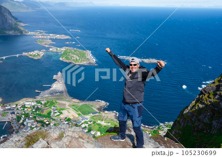 Relaxed happy hiker enjoys stunning views on Reinebringen peaks of Lofoten islands, fjords, Norway 105230699