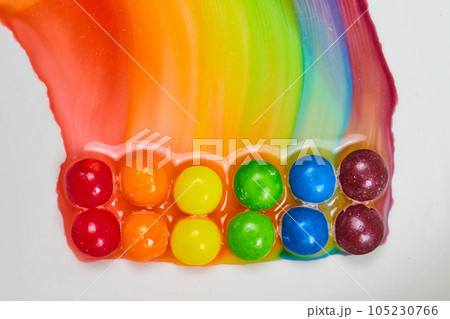 Water colors create tie dye effect as double rainbow colors leak on white background 105230766