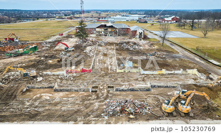Aerial of construction vehicles near a destroyed building with debris 105230769