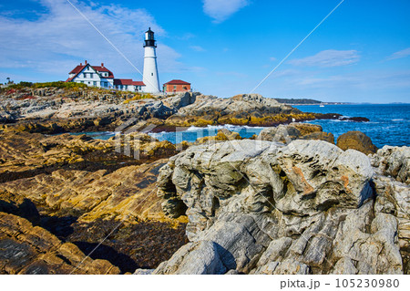 White lighthouse overlooking rocky coast in Maine with focus on rocks like petrified wood White lighthouse overlooking rocky coast in Maine with focus on rocks like petrified wood 105230980