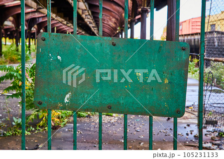 Old green rusted steel gate with decayed train track behind 105231133