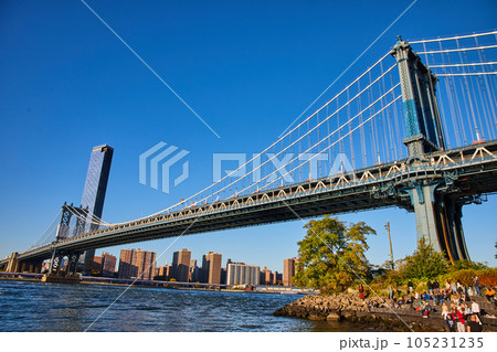 View of entire Brooklyn Bridge from low angle with waters and New York City in background 105231235
