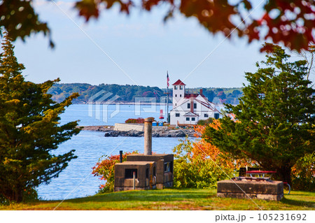 View through forest trees of Maine island housing white home for lighthouse View through forest trees of Maine island housing white home for lighthouse 105231692