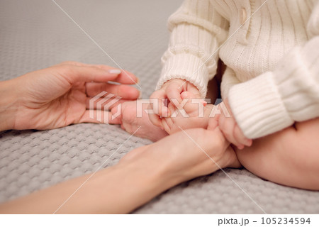Happy Motherhood. Mom's hands holding the baby's little legs. High quality photo 105234594