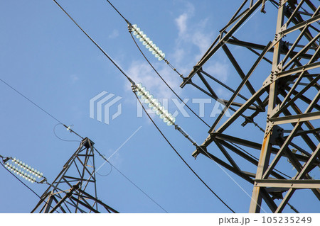 High voltage tower with power wires against the background of the sun and cloud 105235249