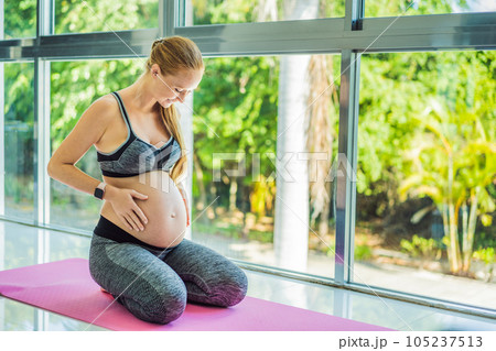 Young pregnant woman doing yoga exercises and meditating at home or yoga studio. Health care, mindfulness, relaxation and wellness concept Young pregnant woman doing yoga exercises and meditating at home or yoga studio. Health care, mindfulness, relaxation and wellness concept 105237513