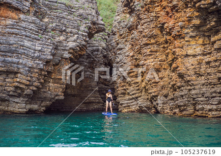 Young women Having Fun Stand Up Paddling in blue water seaamong the rocks in Montenegro. SUP Young women Having Fun Stand Up Paddling in blue water seaamong the rocks in Montenegro. SUP 105237619