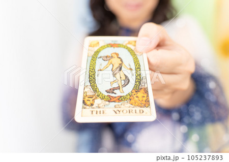 タロットカード（THE WORLD)を差し出す占い師 105237893