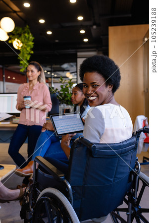 Portrait of happy african american casual businesswomen in wheelchair holding tablet in office Portrait of happy african american casual businesswomen in wheelchair holding tablet in office 105239188