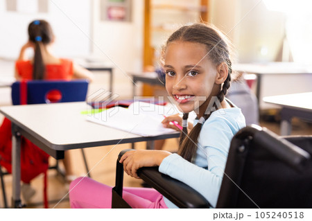 Portrait of happy diverse and disabled schoolgirls in wheelchair writing in classroom Portrait of happy diverse and disabled schoolgirls in wheelchair writing in classroom 105240518