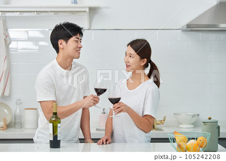 a young couple enjoying wine in the kitchen 105242208