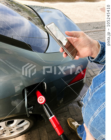 Man making contactless payment using smartphone for refueling car at gas station. Man making contactless payment using smartphone for refueling car at gas station. 105245410