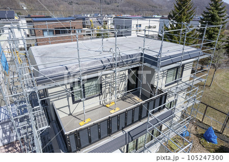 住宅リフォーム 外壁塗装と屋根の張替え作業中の家（空撮） 105247300
