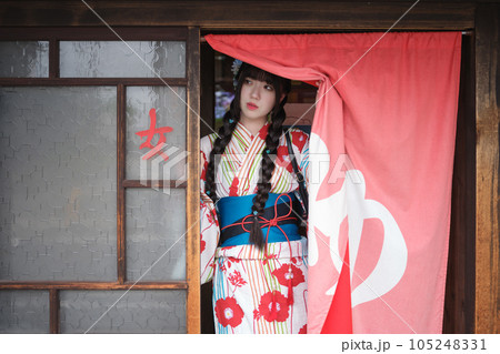 銭湯の暖簾を分けて出てくる浴衣の若い女性 105248331