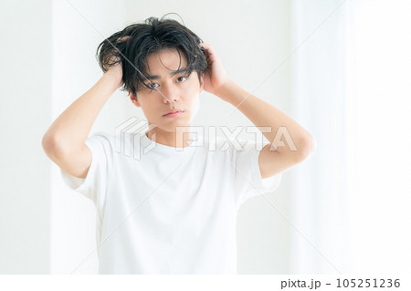 リビングの窓際でヘアケアをする若い男性 リビングの窓際でヘアケアをする若い男性 105251236