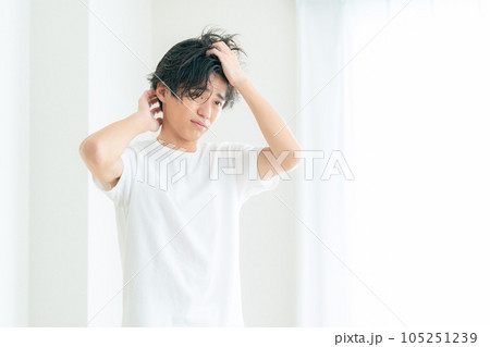 リビングの窓際でヘアケアをする若い男性 リビングの窓際でヘアケアをする若い男性 105251239