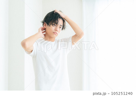 リビングの窓際でヘアケアをする若い男性 リビングの窓際でヘアケアをする若い男性 105251240