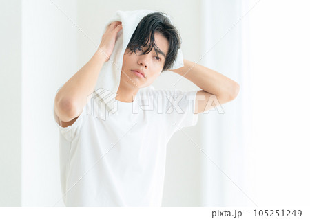 リビングの窓際で髪の毛をタオルで拭くをする若い男性 リビングの窓際で髪の毛をタオルで拭くをする若い男性 105251249