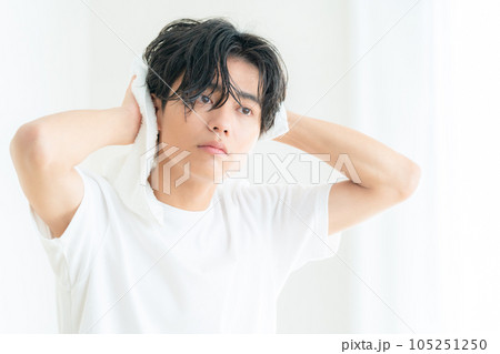 リビングの窓際で髪の毛をタオルで拭くをする若い男性 105251250
