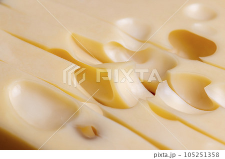 A cut piece of ripe cheese with lots of holes A cut piece of ripe cheese with lots of holes 105251358