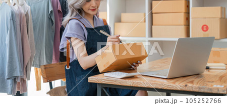 Close up woman designer stylish blogger entrepreneur is write the customer name in front of the box and taking receive online delivery order to prepare packing the product online shopping delivery Close up woman designer stylish blogger entrepreneur is write the customer name in front of the box and taking receive online delivery order to prepare packing the product online shopping delivery 105252766