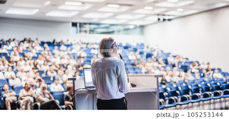 Female speaker giving a talk on corporate business conference. Unrecognizable people in audience at conference hall. Business and Entrepreneurship event 105253144