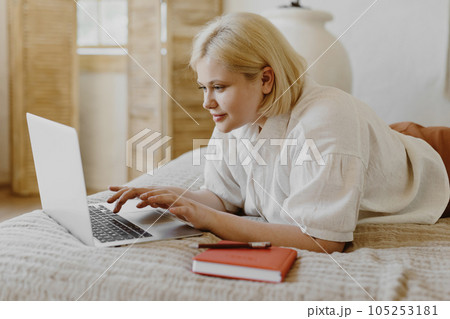Beautiful woman lying in bed and using laptop. 105253181