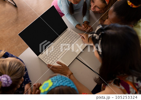 High angle view of diverse female teacher and girls looking at laptop while studying online on table High angle view of diverse female teacher and girls looking at laptop while studying online on table 105253324