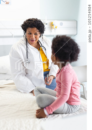 Happy african american female doctor talking to girl patient at hospital Happy african american female doctor talking to girl patient at hospital 105254984