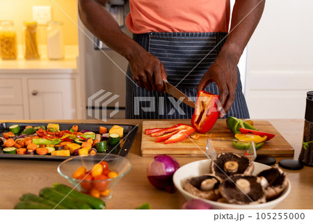 Midsection of african american man chopping vegetables in kitchen Midsection of african american man chopping vegetables in kitchen 105255000