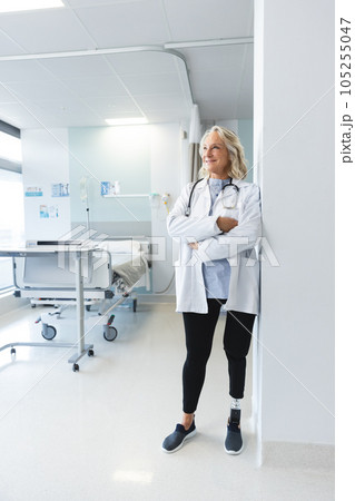 Happy senior caucasian female doctor with artificial leg wearing lab coat at hospital 105255047