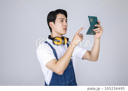 millennials and gen z, korean asian young man carpenter holding a bankbook millennials and gen z, korean asian young man carpenter holding a bankbook 105256495