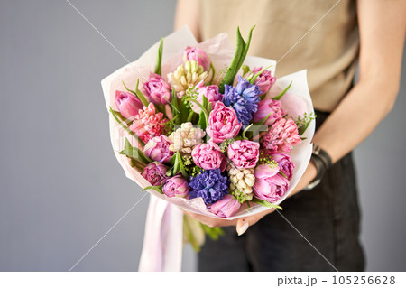 Sunny spring morning. Young happy woman holding a beautiful bunch of hyacinths and tulips in her hands. Present for a smiles girl. Flowers bouquet 105256628