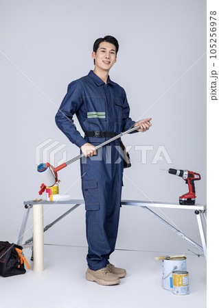millennials and gen z, korean asian young man, site staff sitting holding a paint roller millennials and gen z, korean asian young man, site staff sitting holding a paint roller 105256978