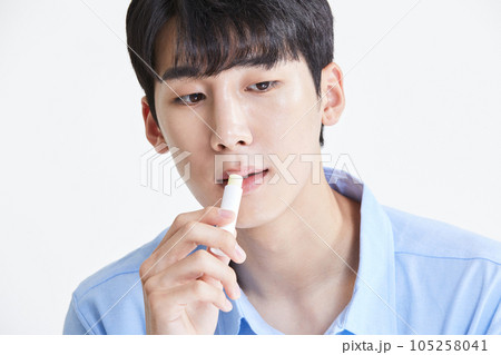 korean asian young man applying lip balm 105258041