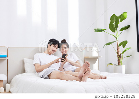 summer lifestyle, korean asian young couple with bed and smartphone summer lifestyle, korean asian young couple with bed and smartphone 105258329