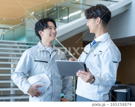 作業服を着てタブレットを見て笑い合う若い男性スタッフ2人 作業服を着てタブレットを見て笑い合う若い男性スタッフ2人 105258874