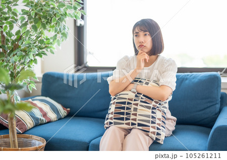 クッションを抱えて考える女性 クッションを抱えて考える女性 105261211