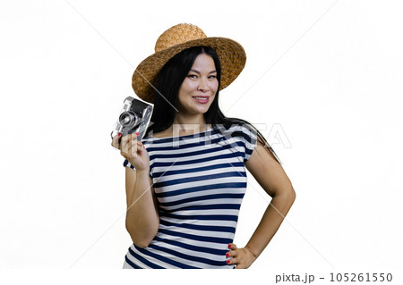 Young asian woman in straw hat is posing with a vintage photo camera. Isolated on white. Young asian woman in straw hat is posing with a vintage photo camera. Isolated on white. 105261550