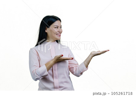 Smiling young cheerful asian woman showing copy space with both hands. Isolated on white background. 105261718