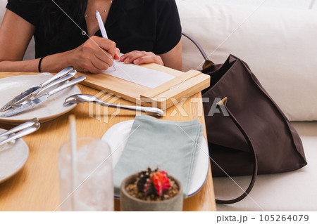 Woman signing slip payment credit card at dinner tale in restaurant. Woman signing slip payment credit card at dinner tale in restaurant. 105264079