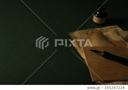 Old letters, ink bottle and pen on green background, space for text Old letters, ink bottle and pen on green background, space for text 105267226