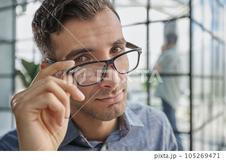 IT guy adjusting glasses in a modern new office IT guy adjusting glasses in a modern new office 105269471