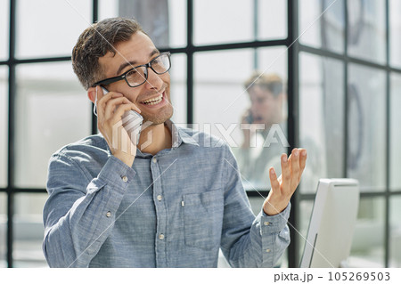 young man in a blue shirt talking on the phone 105269503