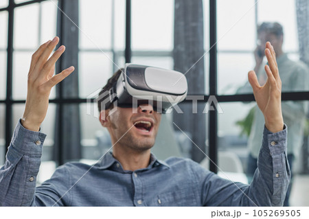 Cool handsome man put on virtual reality goggles for the first time in the office. Cool handsome man put on virtual reality goggles for the first time in the office. 105269505
