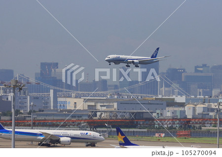 東京の都市を背景に着陸する旅客機　羽田空港に着陸する旅客機 105270094