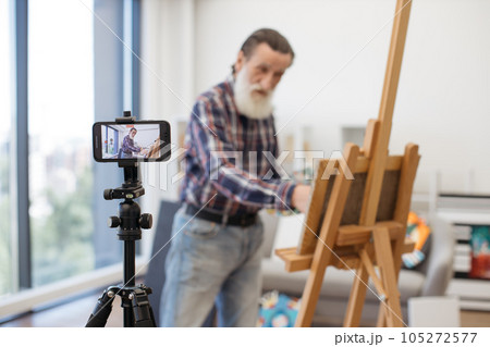Senior art teacher having online class using cellphone 105272577